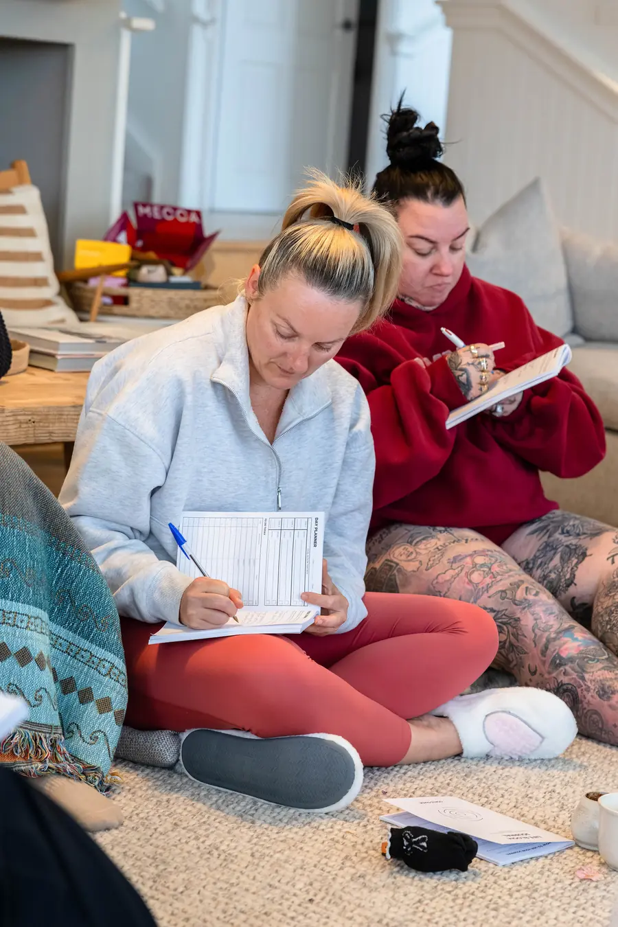Two guests sitting on the floor, writing in their workbooks