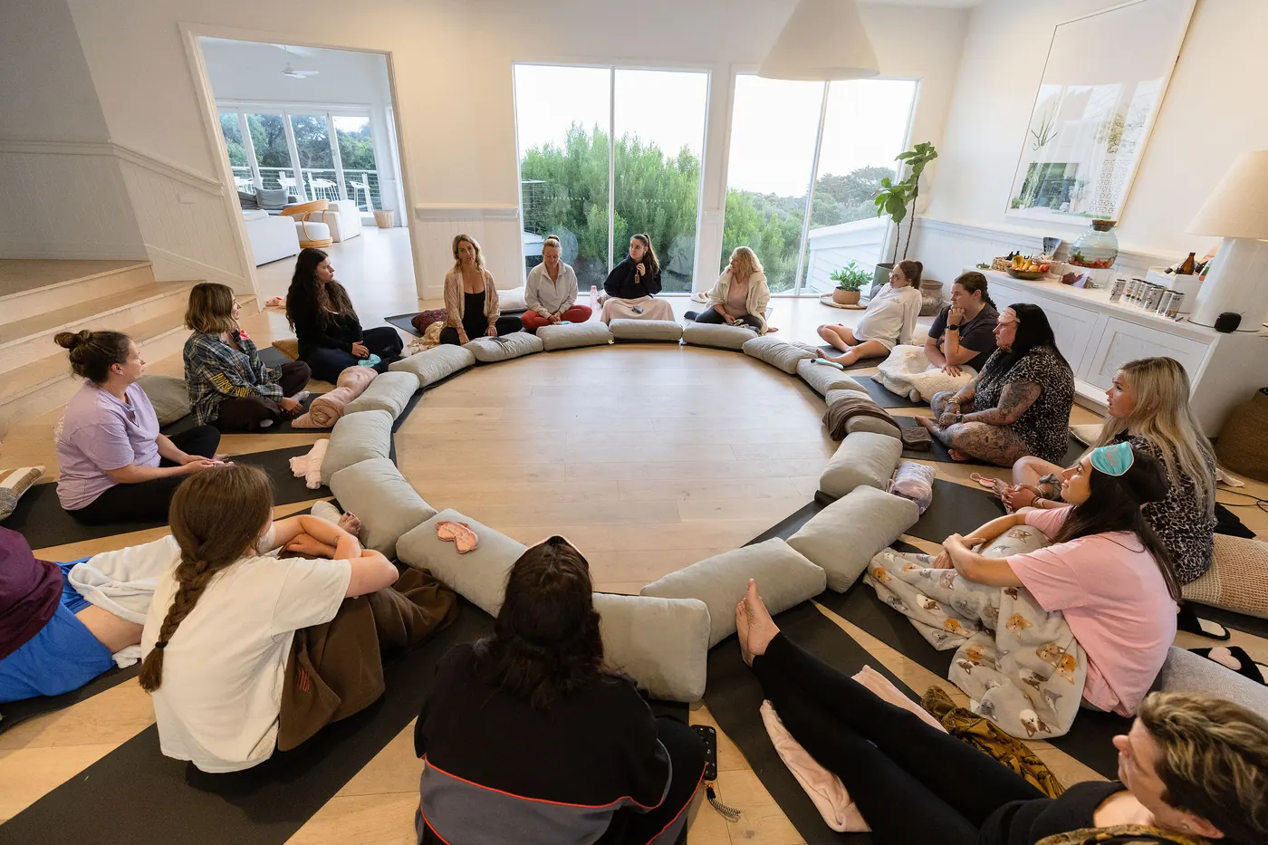Women lying on mats around a ring of bolsters during a breathwork session