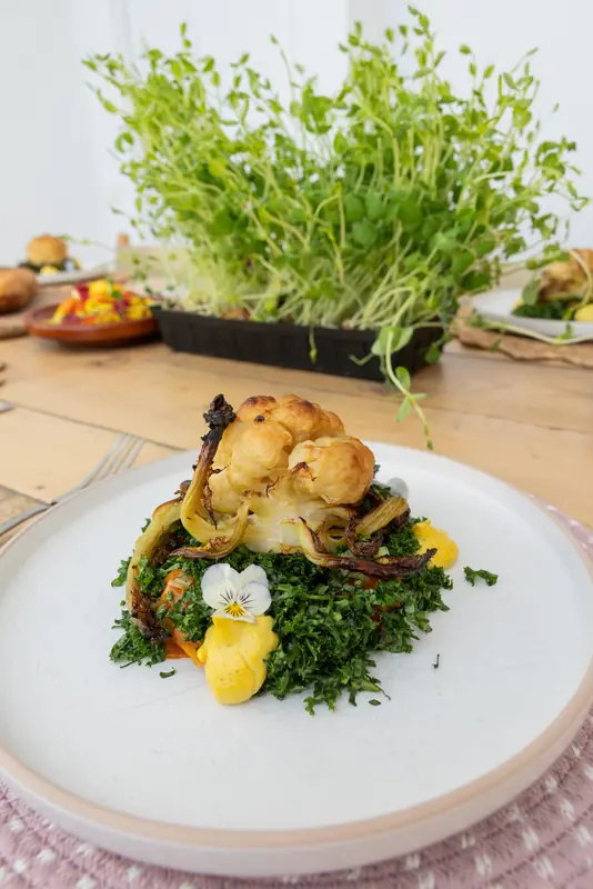 Roasted cauliflower beside a tray of pea shoots