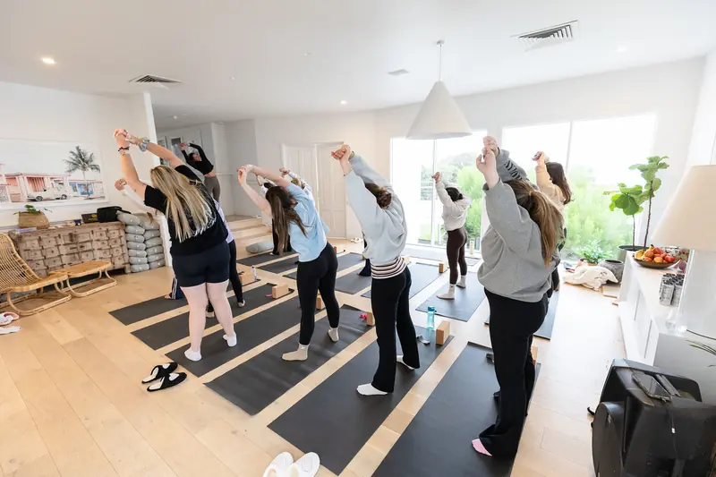A yoga class standing in rows of mats