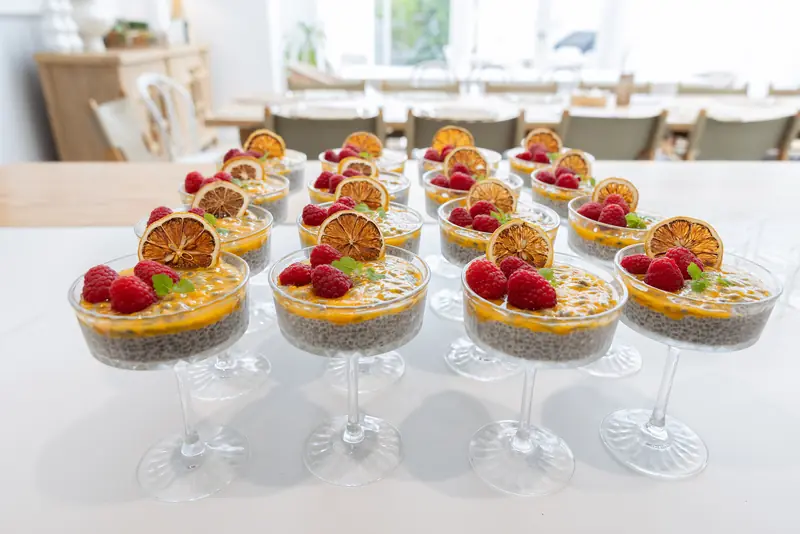 Glasses of chia pudding topped with raspberries and dried orange