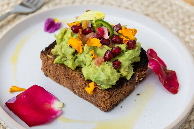 Avocado toast with pomegranate, flowers and rose petals