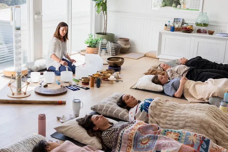 Guests lying down in a sound healing session among crystal bowls