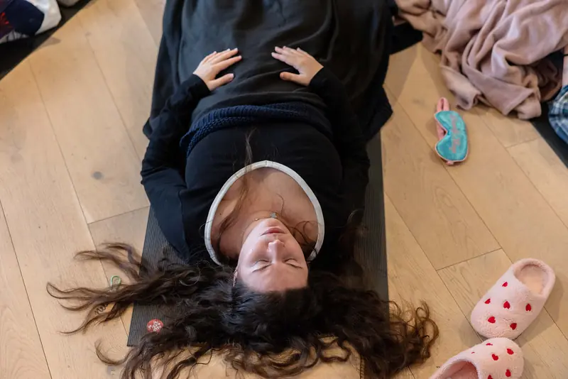 A guest resting on her mat after breathwork, smiling