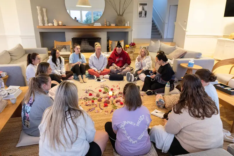 The circle seated around a carpet of rose petals by the fireplace