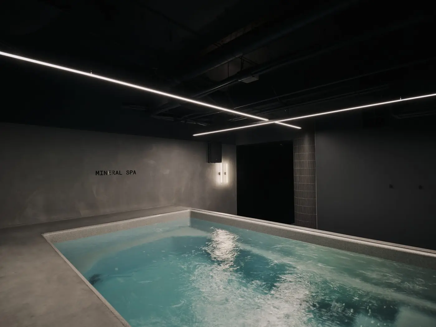 A cold plunge pool, its water bright under a low dark ceiling