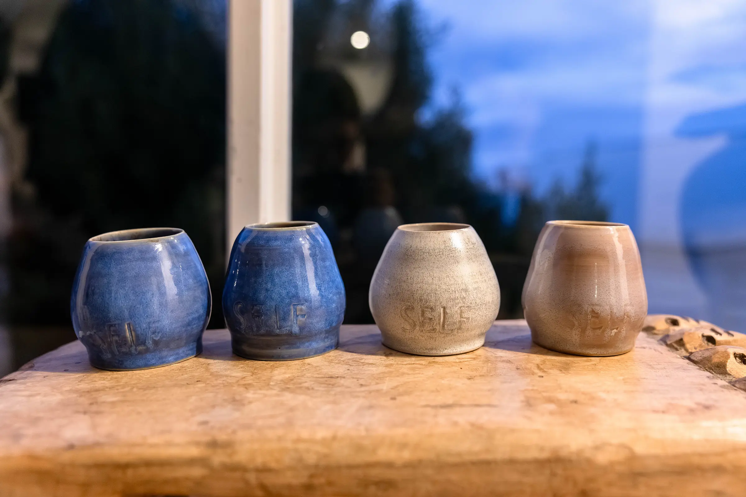 Ceramic cacao cups lined up on a timber table at dusk