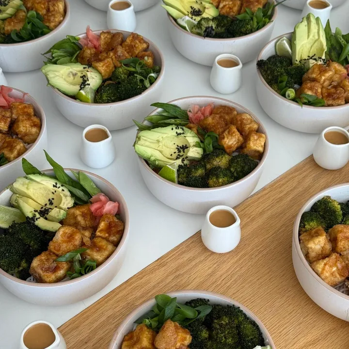 Bowls of crispy tofu, broccoli, avocado and pickled ginger, each with a little jug of dressing