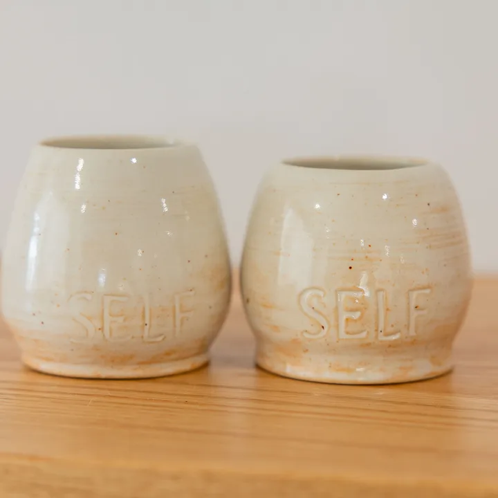 Two handmade SELF cups on a timber table