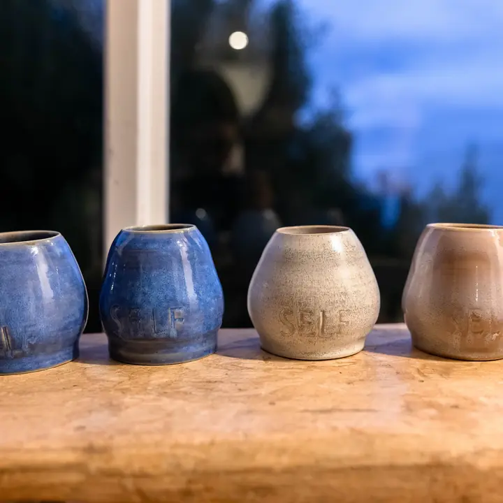 Handmade ceramic cups on a timber ledge at dusk