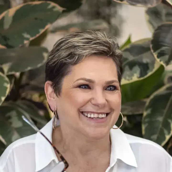 Sue G., co-founder, smiling in an orange jumper