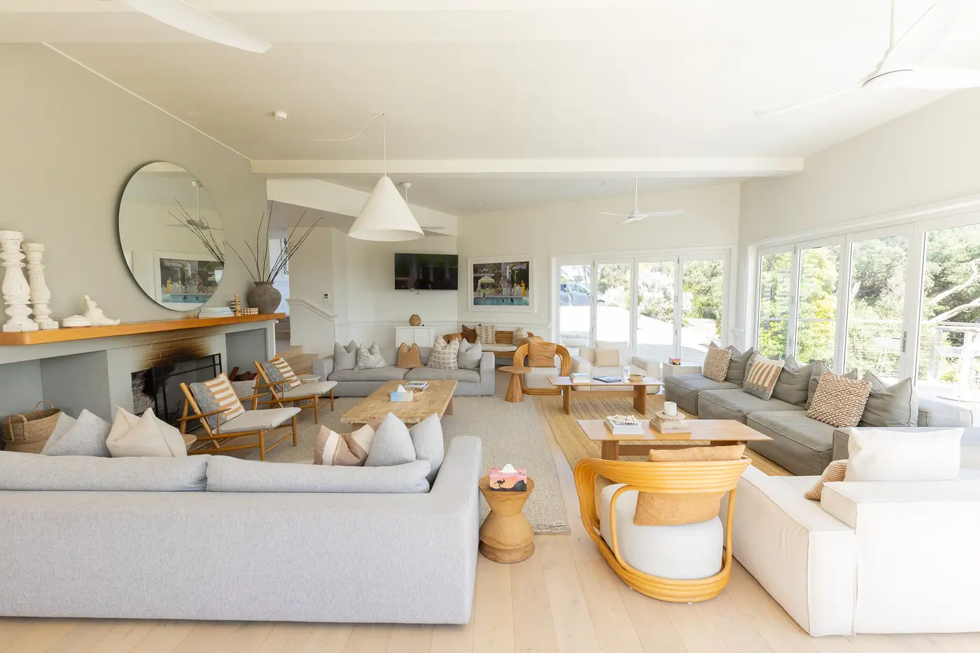 The big open lounge room, with white sofas, a round mirror and the fireplace