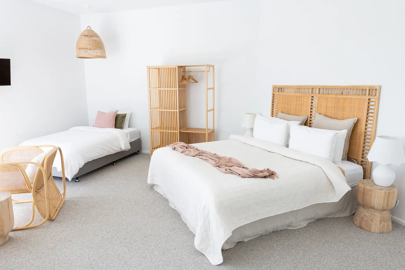 A bright suite with a rattan bedhead and two beds made in white