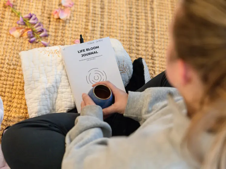 A cup of cacao and a workbook in a guest’s lap
