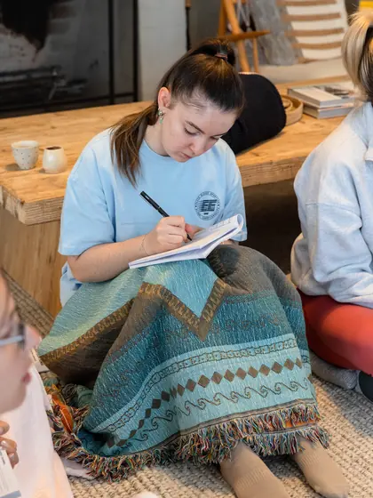 A guest writing in her journal under a woven blanket