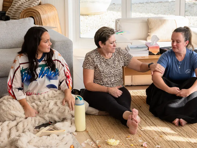 Three guests laughing on the lounge-room floor