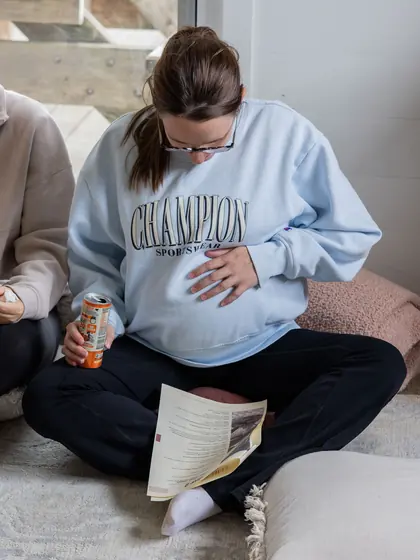 A guest in a big jumper reading her workbook on the floor